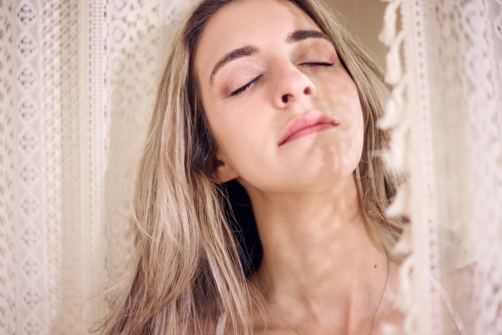 Marissa with her eyes closed, framed by soft cream lace.