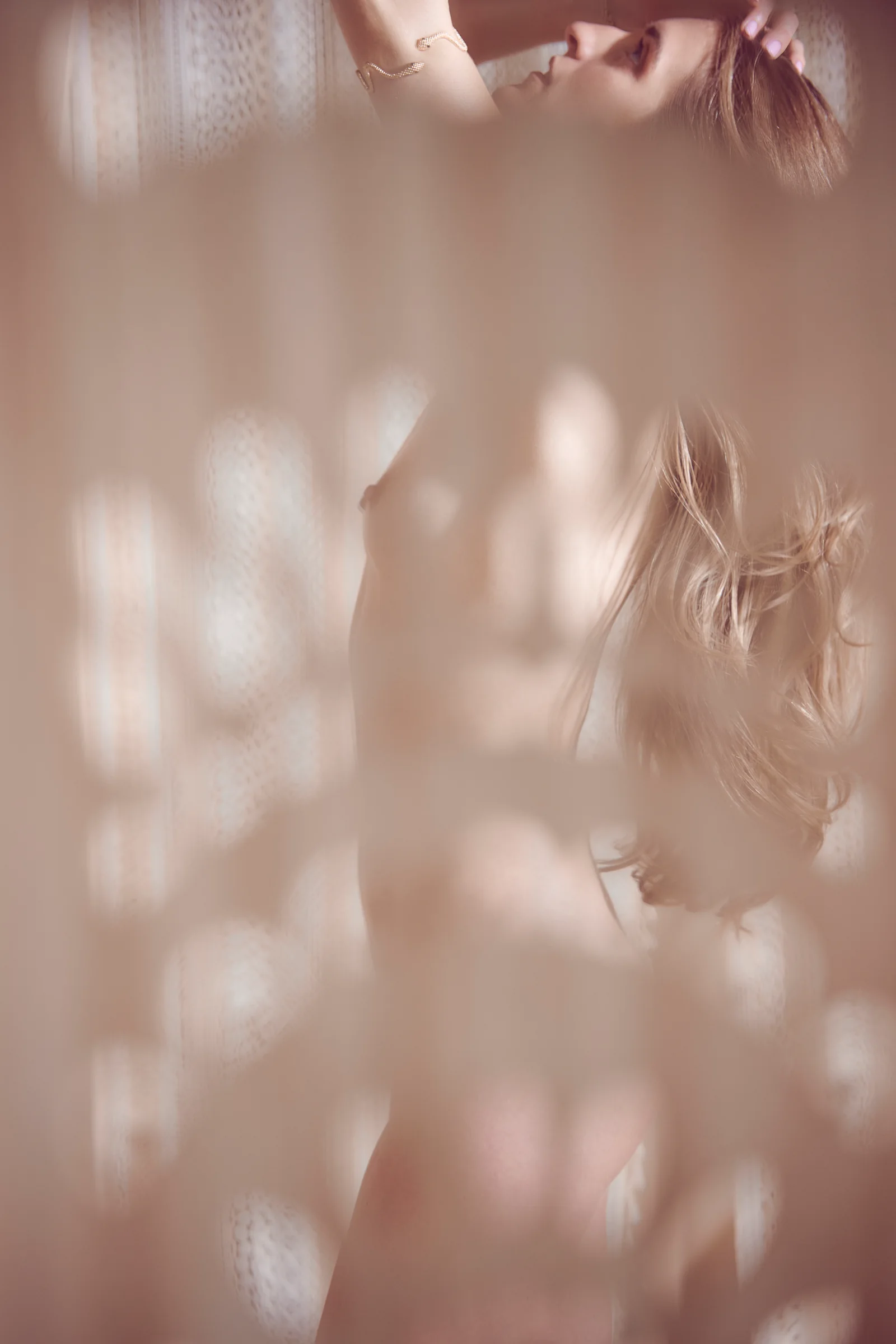 Soft-focus portrait of Marissa behind sheer curtains in dappled light.