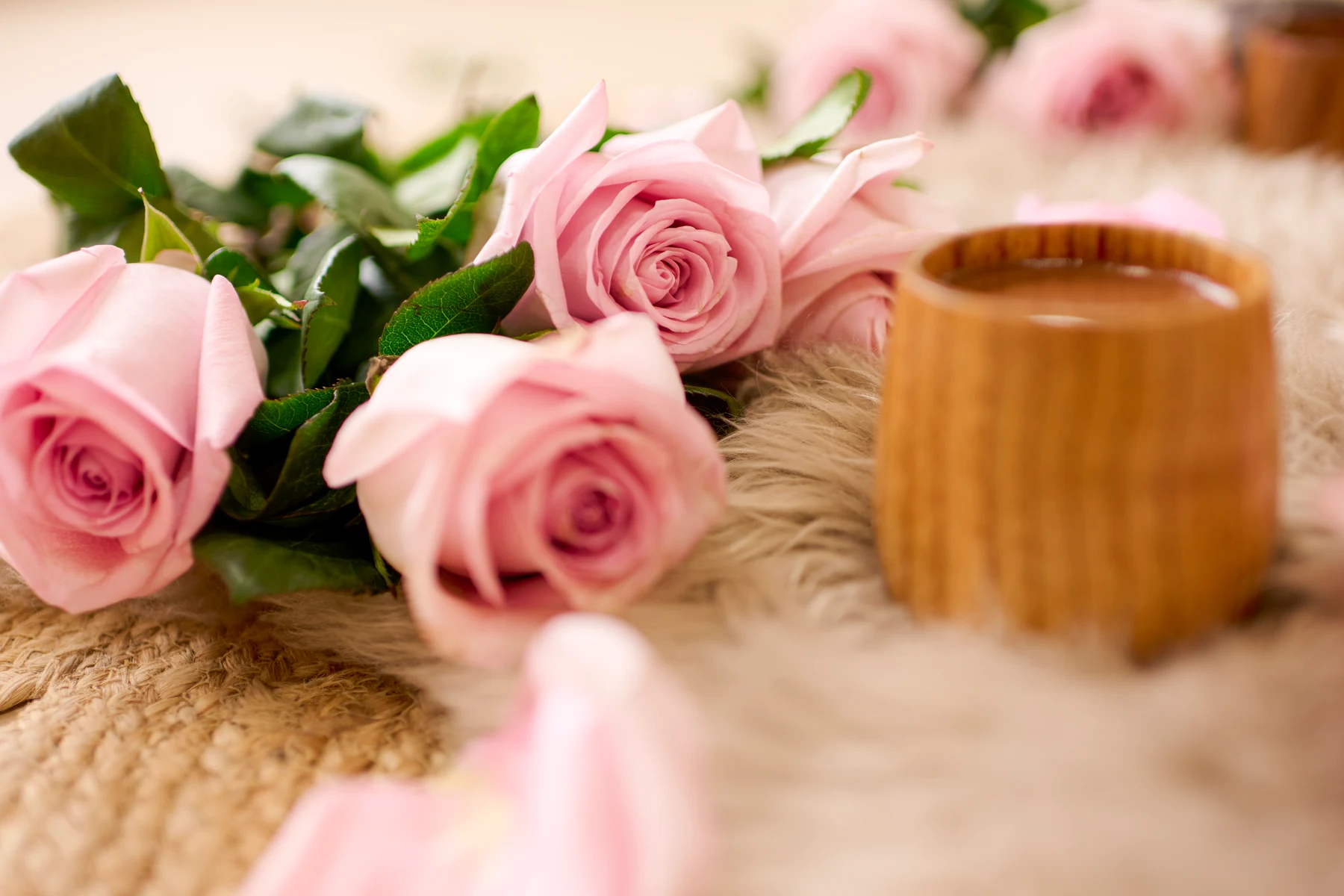Pale pink roses and a wooden cup in a ceremonial arrangement.